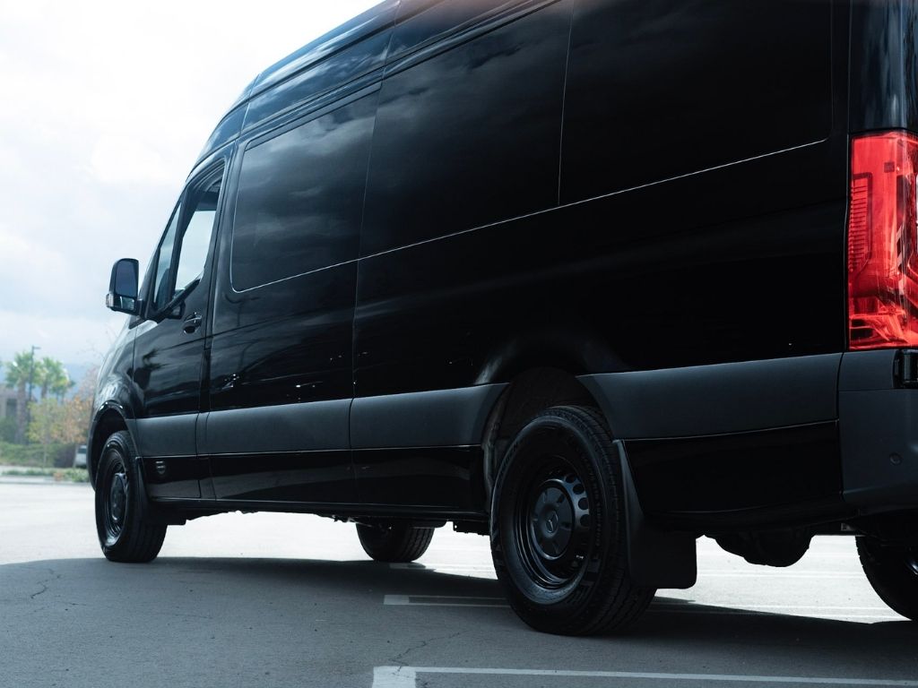 A professional chauffeur standing beside a luxury black limousine representing safe limo services in Orange County